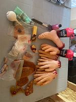 Overview of fake body parts including severed hands, fingers, foot, and makeup bottles including red stage blood on a table.