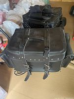 Large black leather motorcycle trunk bag with buckle straps and stud detailing