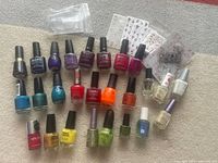 Photo showing 22 nail polish bottles in multiple colors and brands including Mona, Sally Hansen, and others, plus 6 sheets of decorative nail stickers