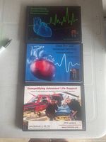 Three DVD sets stacked on a surface, with medical illustrations and instructor photos on covers.