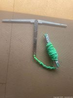Underwater weed trimmer showing metal blade with rust and attached bright green pull rope coiled and taped at handle