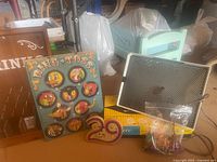 Vintage games including Ring Toss board, Drinko game, Yahtzee box, and Lite-Brite pegboard with pegs and cards visible