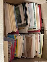 Stack of folded greeting cards and envelopes in various sizes and colors packed closely together.