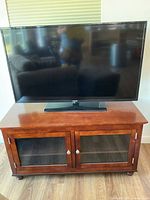 Samsung 52" flat screen TV on wooden media cabinet with smoked glass doors.