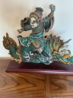 Front view of ceramic Chinese warrior riding dragon mounted on wood base