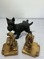 Front view of the two metal dog bookends and the cast iron Scotty dog figurine laid on a table against a plain background.