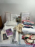 Wide view showing Victorian sewing patterns, fabric pieces, interfacing, and quilting blocks arranged on a flat surface.