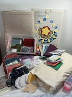 Wide view showing quilting forms, pre-cut fabrics, muslin, and templates arranged on table.