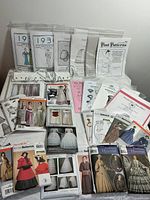 Collection of various vintage and reproduction sewing patterns laid on a white surface.