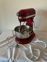 Full view of red KitchenAid Professional 5 Plus stand mixer with stainless steel bowl and three attachments