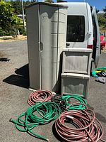 Front view of Rubbermaid cabinet, two Suncast boxes stacked, and hoses in foreground