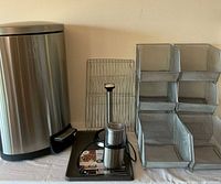 Photo showing large stainless steel trash can, mesh baskets, cooling racks, paper towel holder, griddle, and Shardor blender.