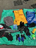 Lot contents displayed on green tarp showing dry bags, shoes, gloves, socks, inflatable belt refill kit and cases.