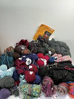 Overview of yarn skeins and unfinished knit pieces showing colors and textures