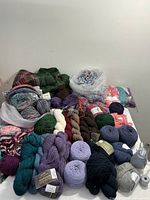 Wide view of yarn skeins, balls, and knitting projects arranged on surface