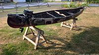 Side view of 16 ft camouflage hunting canoe on wooden stands with Gamefisher motor attached