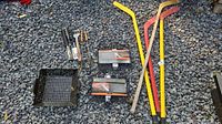 Overview of hockey sticks, grill baskets, grill wok and utensils on ground