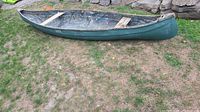 Side view of entire canoe on grass showing overall shape and color