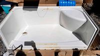 Top view of unused MAAX white acrylic tub with integrated seat and drain opening