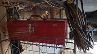 Red metal toolbox and extension cord visible in storage rack