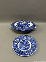 Blue and white English transferware covered casserole dish and plate set on neutral background