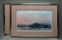 Two landscape lithographs in pink mats and metallic frames featuring serene natural scenes with water and mountains.