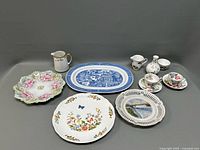 Full group shot of miscellaneous porcelain items including plates, platters, cups, saucers, vase, and creamers showing designs and layout