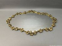 Oval gilt metal framed vanity tray with detailed floral design and mirror base.