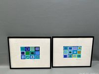 Photo showing front view of the two abstract paintings side by side in black frames on a gray background