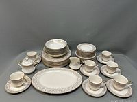 Porcelain dinnerware set arranged showing stacked plates, platter, serving bowl, and cup sets.