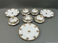 Partial set of cups, saucers, and salad plates showing gold tulip designs and gold trim around the edges.