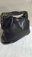 Front and side view of black leather hobo handbag
