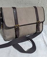Front view showing flap, buckles, strap, canvas and leather materials