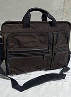 Front view showing canvas material, twin handles, front zip compartments, shoulder strap