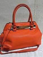 Front view showing Vince Camuto plaque, handles, detachable strap