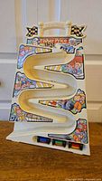 Front view of 1991 Fisher-Price Tumbling Racers vertical race track with three racers at the bottom. Colorful decals and intact structure visible.