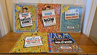 Five Where's Waldo books arranged upright and flat on surface: The Fantastic Journey, Find Waldo Now, Where's Waldo?, The Great Waldo Search, and Where's Waldo in Hollywood.