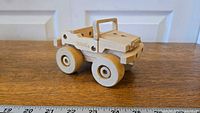 Front angled view of wooden Tonka Jeep toy showing simple body and wheels on wood surface with measurement markings.