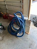 Coiled blue pool hose beside cardboard carton