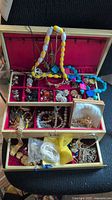 Overall view of open wooden jewelry box filled with assorted jewelry