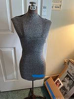 Full frontal view of grey fabric dress form on stand