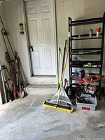 Garage corner with long-handled tools, broom head, rakes