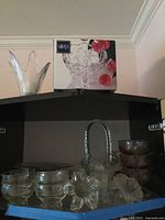 Shelf showing boxed Mikasa bowl, flared vase, various clear glass pieces