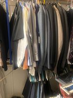 Closet rod with multiple suit jackets and dress shirts, hangers visible