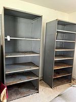 Front view of both metal shelving units showing shelves and rust