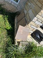 Three square concrete pavers leaning against stone wall