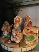 Front view of all Pendelfin rabbits arranged on circular stand with piano