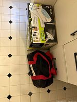 Closed box of Tobi garment steamer and black bag on floor