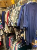 Rack of assorted men’s XL polo shirts and t-shirts on hangers, some with tags visible