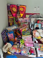 Overview showing the variety of boxed and loose toys including Super Soaker sets, Barbie, VTech toy, plush bin